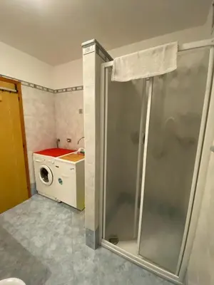 a bathroom with a shower and a washing machine at Cesa Bernard - Aloch in Pozza di Fassa