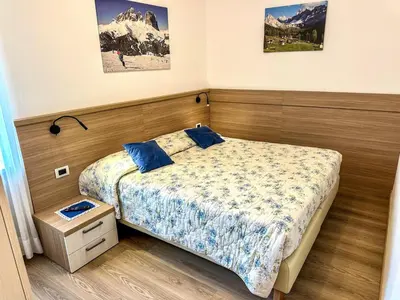 a bedroom with a bed with blue pillows on it at Cesa Bernard - Aloch in Pozza di Fassa