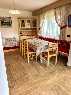 a dining room with a table and chairs and a couch at Cesa Bernard - Aloch in Pozza di Fassa