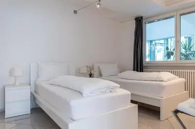 two white beds in a room with a window at Artist House in Merano