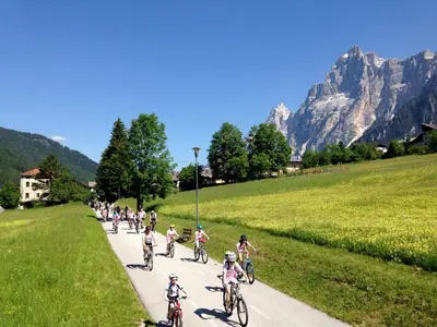 a group of people riding bikes down a path in the mountains at Ciasa Coleto in San Vito di Cadore
