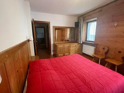 a bedroom with a red bed with a red blanket at Ciasa Coleto in San Vito di Cadore