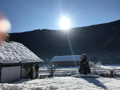 a house covered in snow with the sun behind it at Mahrhof zu Adlitzhausen in Scandole