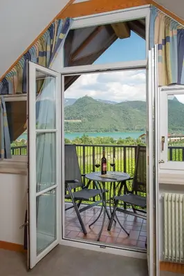 a room with a balcony with a table and a view at Garni Osannahöfl in Caldaro