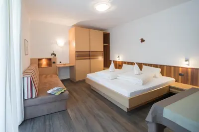 a hotel room with a bed and a couch at Garni Osannahöfl in Caldaro