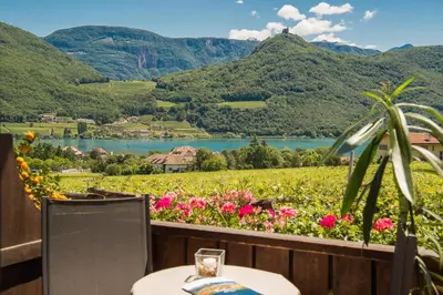 a table and chairs with a view of a river and mountains at Garni Osannahöfl in Caldaro