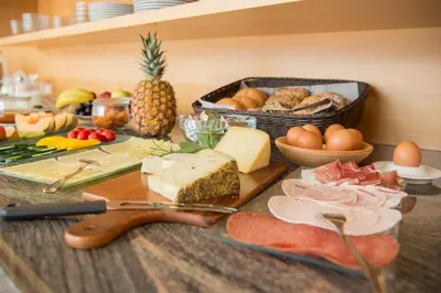 a table with cheese and other foods on it at Garni Osannahöfl in Caldaro