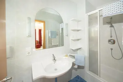 a white bathroom with a sink and a shower at Garni Osannahöfl in Caldaro