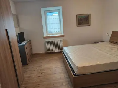a bedroom with a bed and a dresser and a window at Appartamento Maria appartamento nelle dolomiti in Canale San Bovo