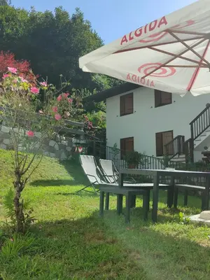 a table and chairs under an umbrella in front of a house at Appartamento Maria appartamento nelle dolomiti in Canale San Bovo