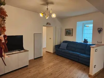 a living room with a blue couch and a television at Appartamento Maria appartamento nelle dolomiti in Canale San Bovo