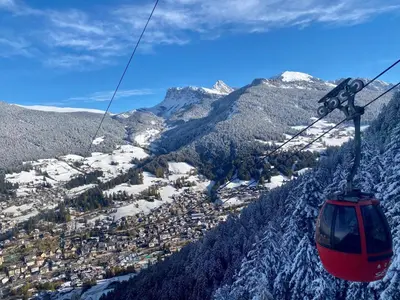 a red gondola flying over a snowy mountain at Apartments Praverd nelle Dolomiti in Santa Cristina in Val Gardena