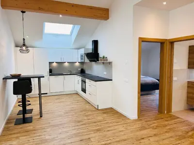 a kitchen with white cabinets and a table and a bed at Apartments P19 nelle Dolomiti in Ortisei