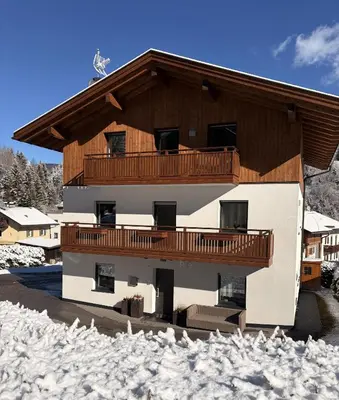 a building with a balcony with snow on the ground at Apartments P19 nelle Dolomiti in Ortisei