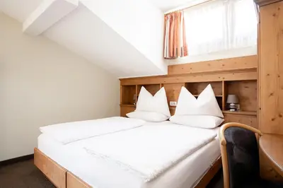 a bedroom with two beds and a window at Hotel Euròpa Dolomites in Selva di Val Gardena