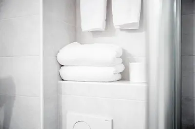 a stack of towels on a shelf in a bathroom at Hotel Euròpa Dolomites in Selva di Val Gardena