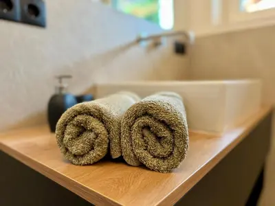 a pile of towels on a counter next to a sink at Lilena Apartment in Merano