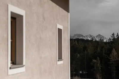 two windows of a building with a view of a forest at Haus Engadein in Auna di Sopra