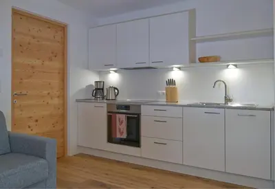 a kitchen with white cabinets and a sink at Hofrichter in San Lorenzo di Sebato