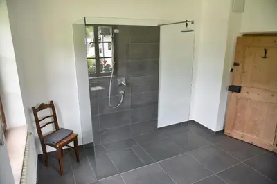 a bathroom with a shower with a wooden chair and a chair at Hofrichter in San Lorenzo di Sebato
