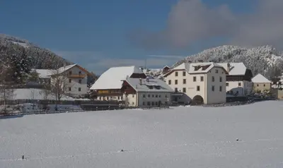 a group of buildings with snow on the ground at Hofrichter in San Lorenzo di Sebato