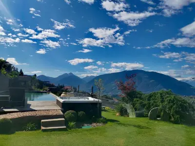a backyard with a swimming pool and mountains at Lifestyle Hotel Alpin in Schenna
