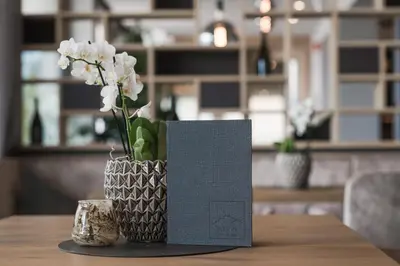 a vase with white flowers and a card on a table at Lifestyle Hotel Alpin in Schenna