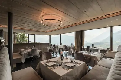a restaurant with tables and chairs and windows at Lifestyle Hotel Alpin in Schenna