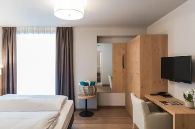 a hotel room with a bed and a desk and a television at Lifestyle Hotel Alpin in Schenna