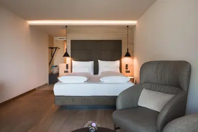a bedroom with a large bed and a chair at Lifestyle Hotel Alpin in Schenna