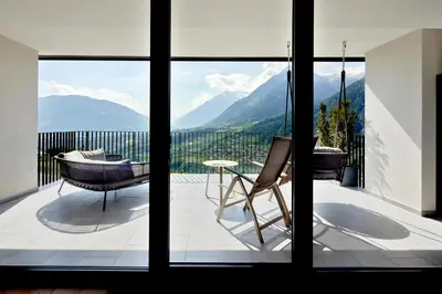a balcony with a view of mountains through a window at Lifestyle Hotel Alpin in Schenna