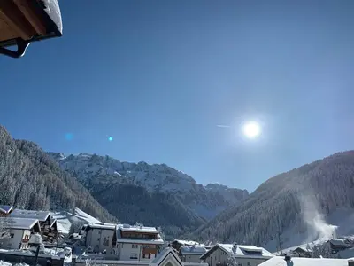 a town in the mountains with the sun in the sky at Hotel Garni Broi - Charme & Relax in Selva di Val Gardena