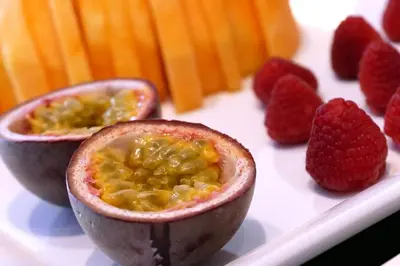 a fruit cut in half on a plate with raspberries at Hotel Garni Broi - Charme & Relax in Selva di Val Gardena