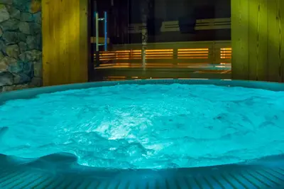 a hot tub with blue water in a room at Hotel Garni Broi - Charme & Relax in Selva di Val Gardena