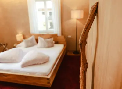 a bedroom with a bed with white sheets and pillows at Hotel Villa Freiheim in Merano
