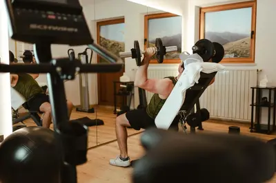 a man lifting weights in a gym at Hotel Villa Freiheim in Merano