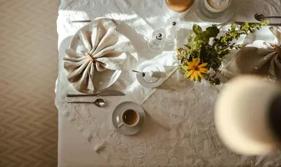 a white table with flowers and a cup of coffee at Hotel Villa Freiheim in Merano