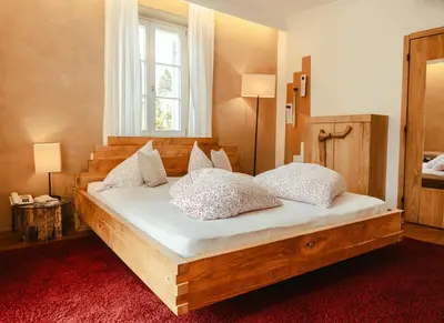 a bedroom with a large wooden bed with pillows at Hotel Villa Freiheim in Merano