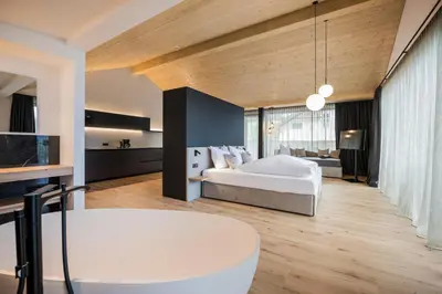 a large bedroom with a bed and a table at Montanaris Alpine - Active - Relax in Villabassa