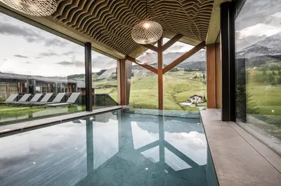 a house with a swimming pool with a view of the mountains at Miraval NaturHotel in Badia