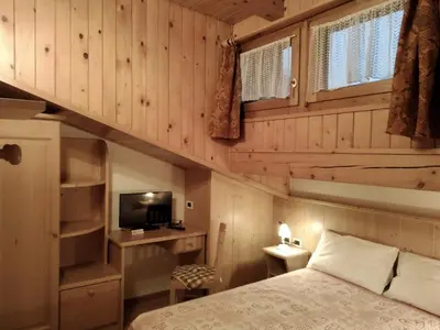a bedroom with wooden walls and a bed and a tv at Hotel Garnì Miramonti in Falcade