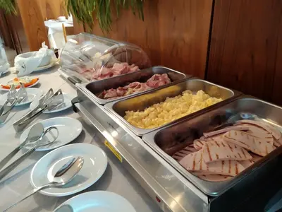 a table with a tray of meat and scrambled eggs at Hotel Garnì Miramonti in Falcade