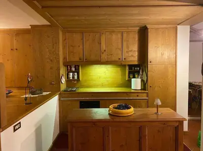a kitchen with wooden cabinets and a wooden island at Casa Peragallo Cortina in Cortina dʼAmpezzo