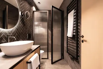 a bathroom with a white sink and a shower at Schwarzer Adler - Concept Living in Vipiteno