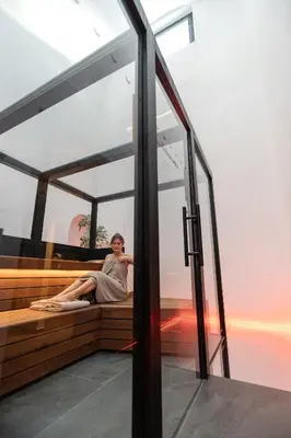 a woman sitting on a bench next to a window at Schwarzer Adler - Concept Living in Vipiteno