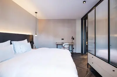 a bedroom with a large white bed and a desk at Schwarzer Adler - Concept Living in Vipiteno