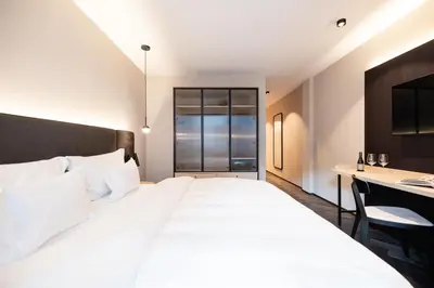 a bedroom with a large white bed and a desk at Schwarzer Adler - Concept Living in Vipiteno