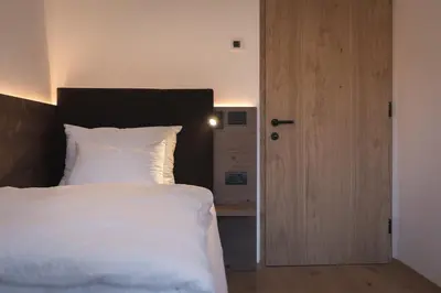 a bedroom with a white bed and a wooden door at Sottla - your mountain home in Valdaora