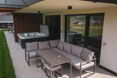 a patio with a couch and a table and a tub at Sottla - your mountain home in Valdaora