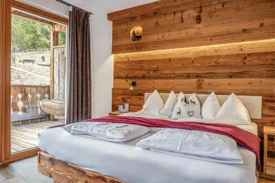 a bedroom with a large bed with a wooden wall at Alpine Mountain Chalet in San Vigilio Di Marebbe